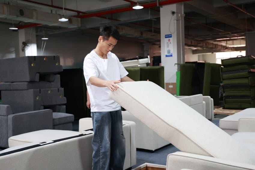 A man is inspecting and doing quality assurance on Zen Living Furniture couch in factory.
